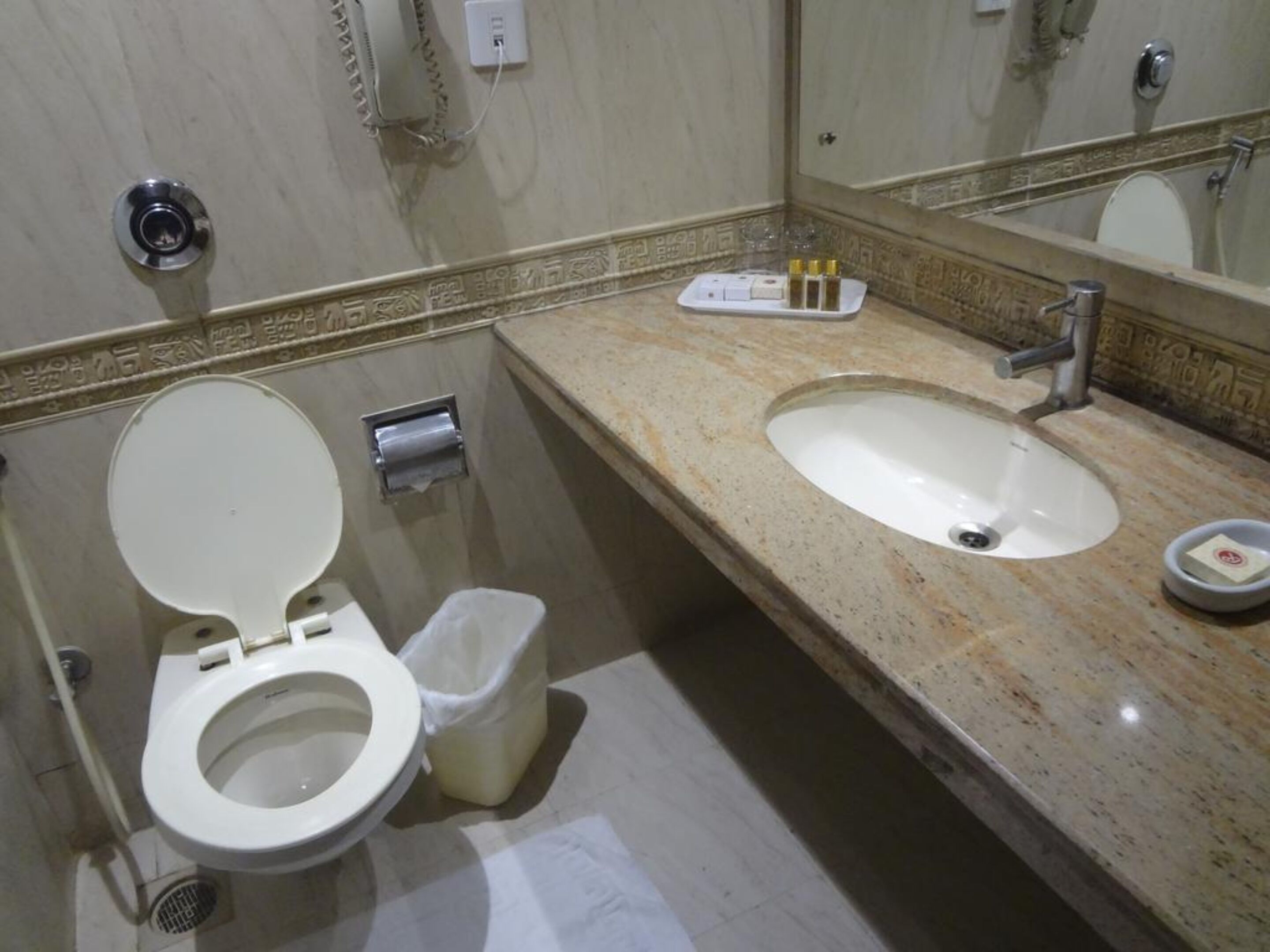 A bathroom with a toilet, sink, and a trash bin.