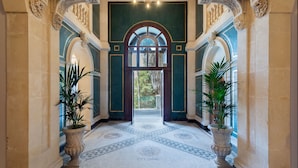 A grand hallway with ornate columns, a tiled floor, and large potted plants. - Grand Hotel Des Ètrangers - The Leading Hotels of the World (Syracuse)