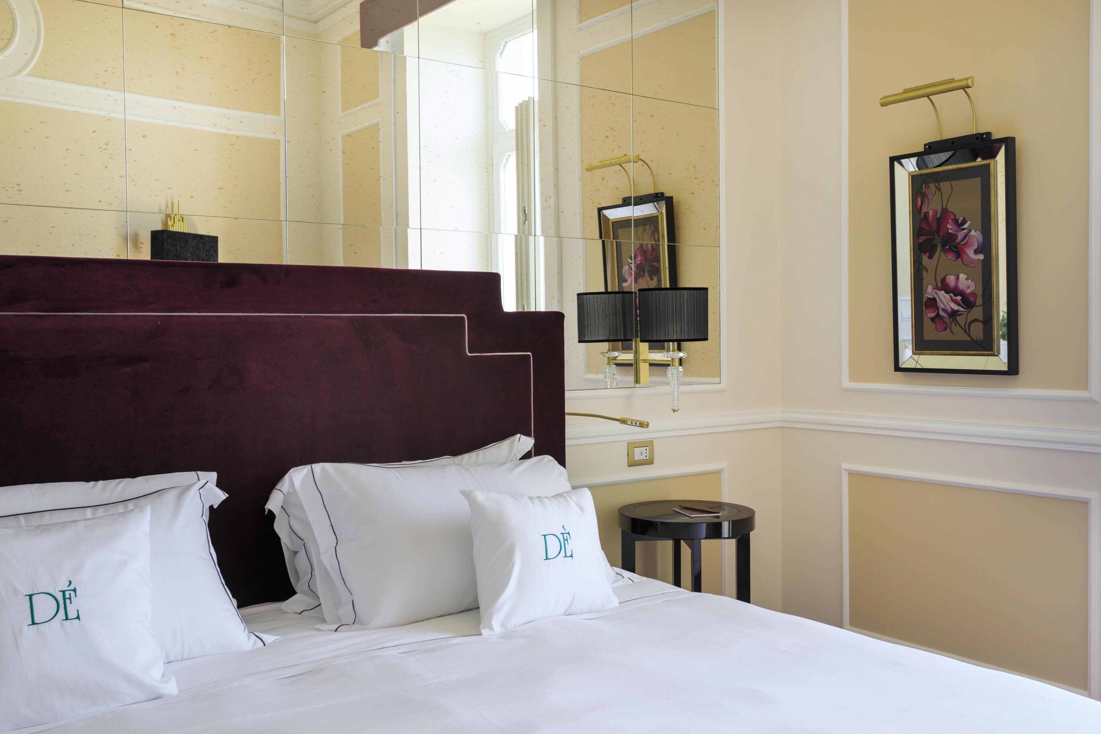 Una camera d'albergo con un letto grande, una testata del letto scura e un comodino con una lampada.