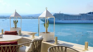 A terrace with a view of the sea and a cruise ship, featuring outdoor seating and potted cacti. - Grand Hotel Des Ètrangers - The Leading Hotels of the World (Syracuse)