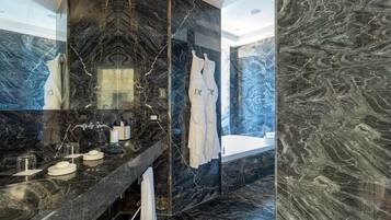 Un baño moderno con tocador de mármol negro, cabina de ducha de vidrio y bañera.