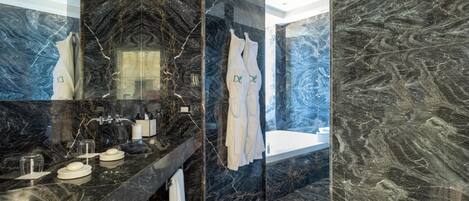 Un baño moderno con tocador de mármol negro, cabina de ducha de vidrio y bañera.