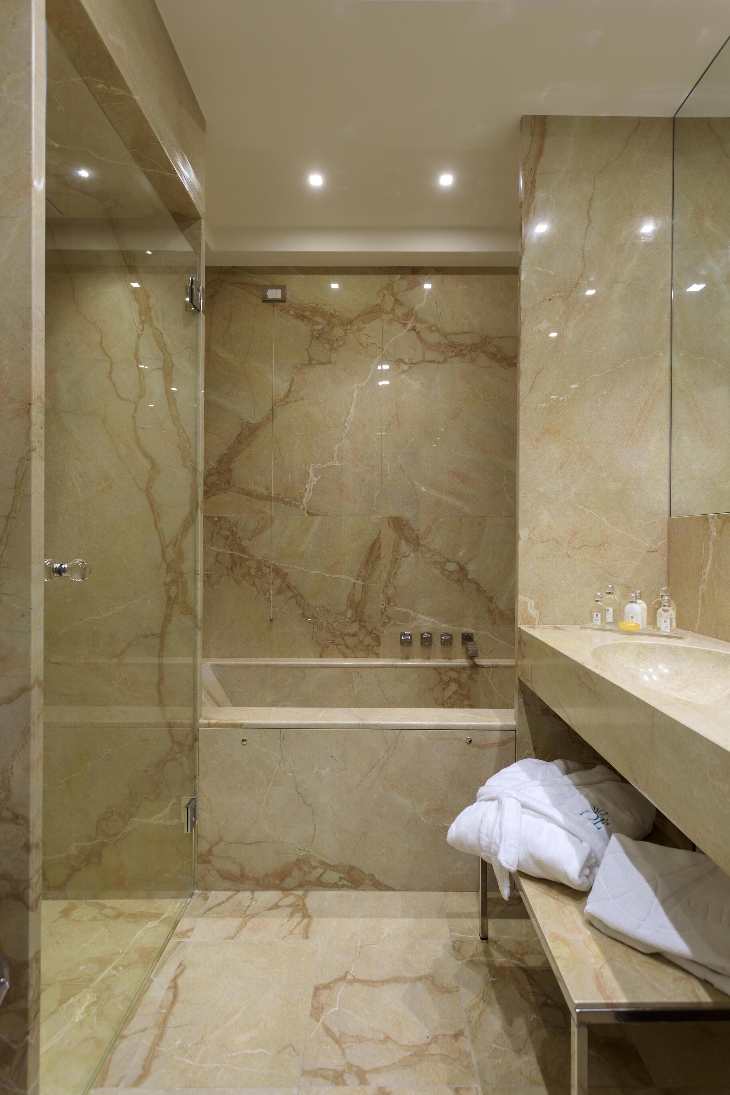 A modern bathroom with a marble shower, a glass-enclosed walk-in shower, and a vanity with a mirror.