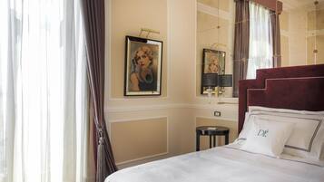 A hotel room with a large bed, a mirror, a painting on the wall, and a window with curtains.