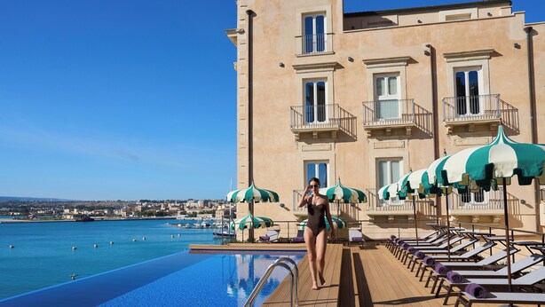 A poolside area with lounge chairs and umbrellas, a clear blue pool, and a building with balconies. - Grand Hotel Des Ètrangers - The Leading Hotels of the World (Syracuse)