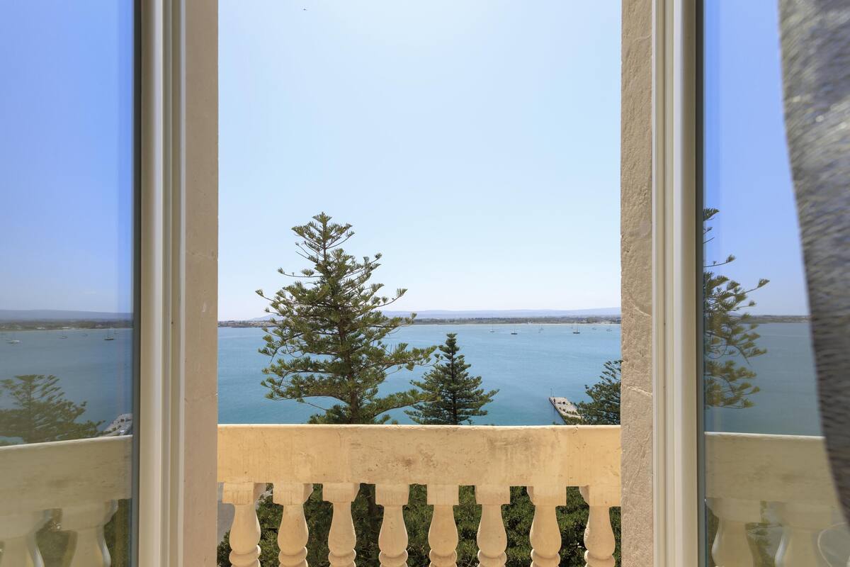 A balcony with a view of the sea and trees.