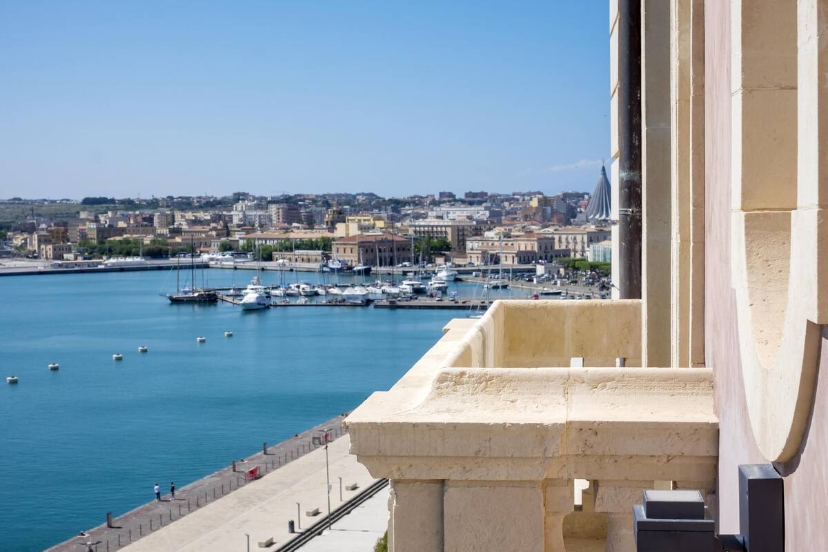 A harbor with boats, a clear sky, and buildings in the background.