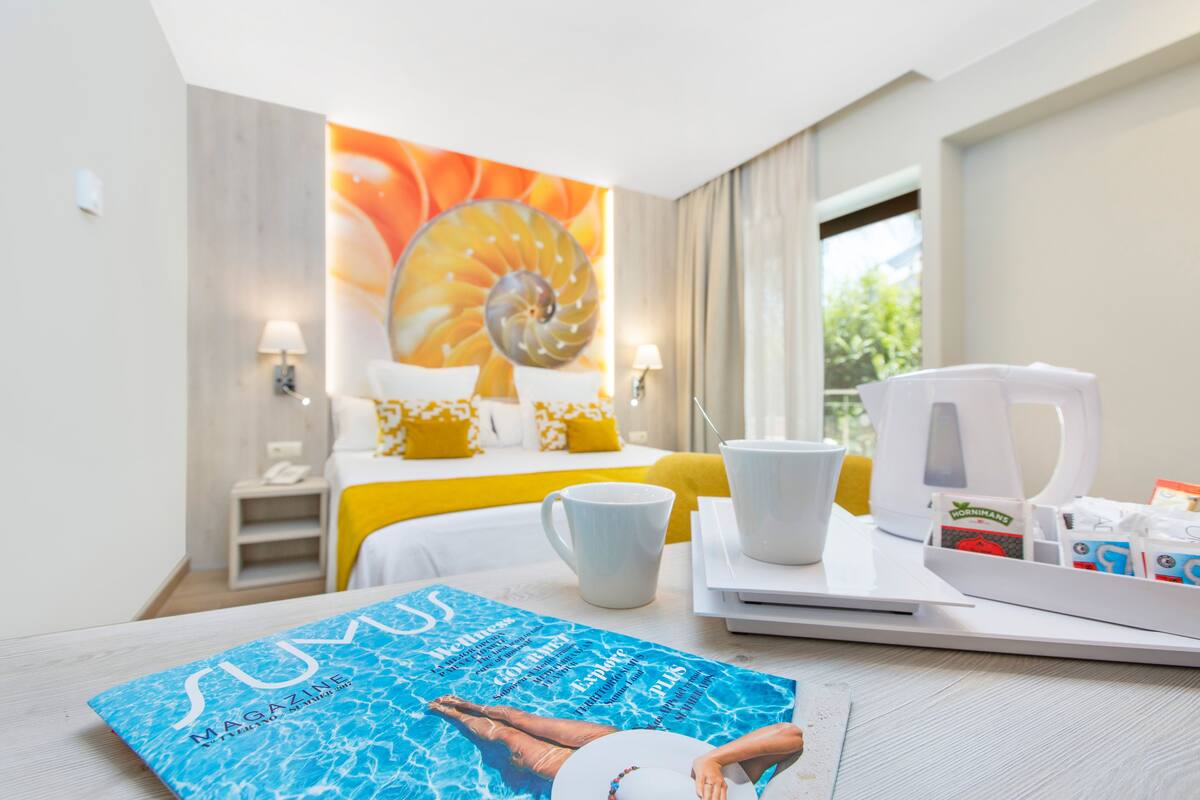 A hotel room with a bed, a coffee table, a breakfast tray, and a large painting on the wall.