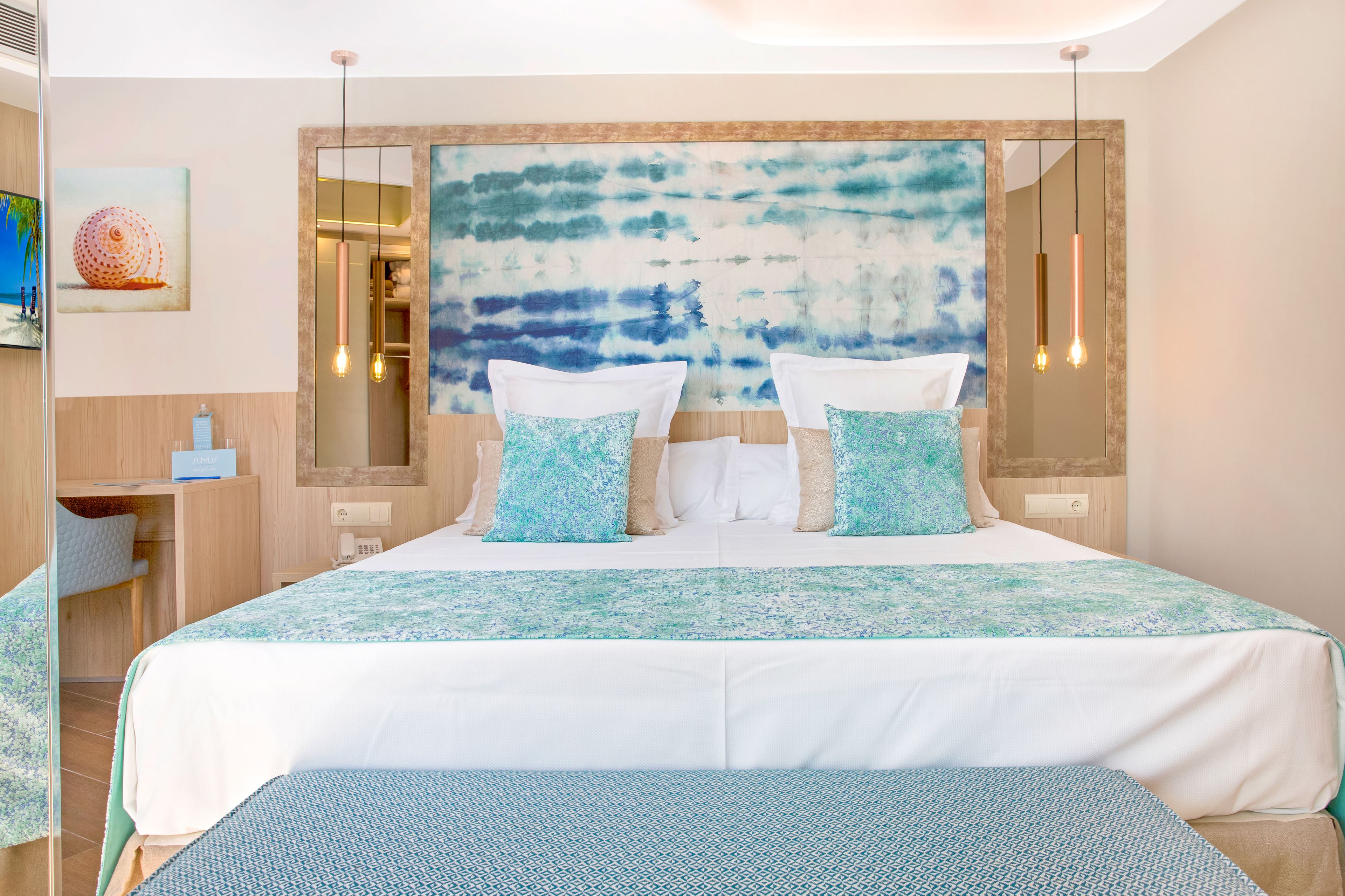 Een hotelkamer met een groot bed, een nachtkastje, een spiegel en uitzicht op zee.