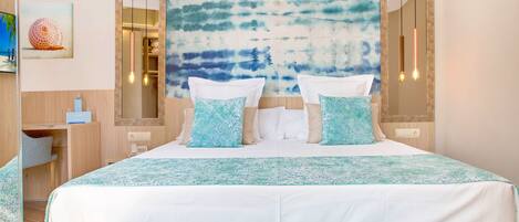 Een hotelkamer met een groot bed, een nachtkastje, een spiegel en uitzicht op zee.