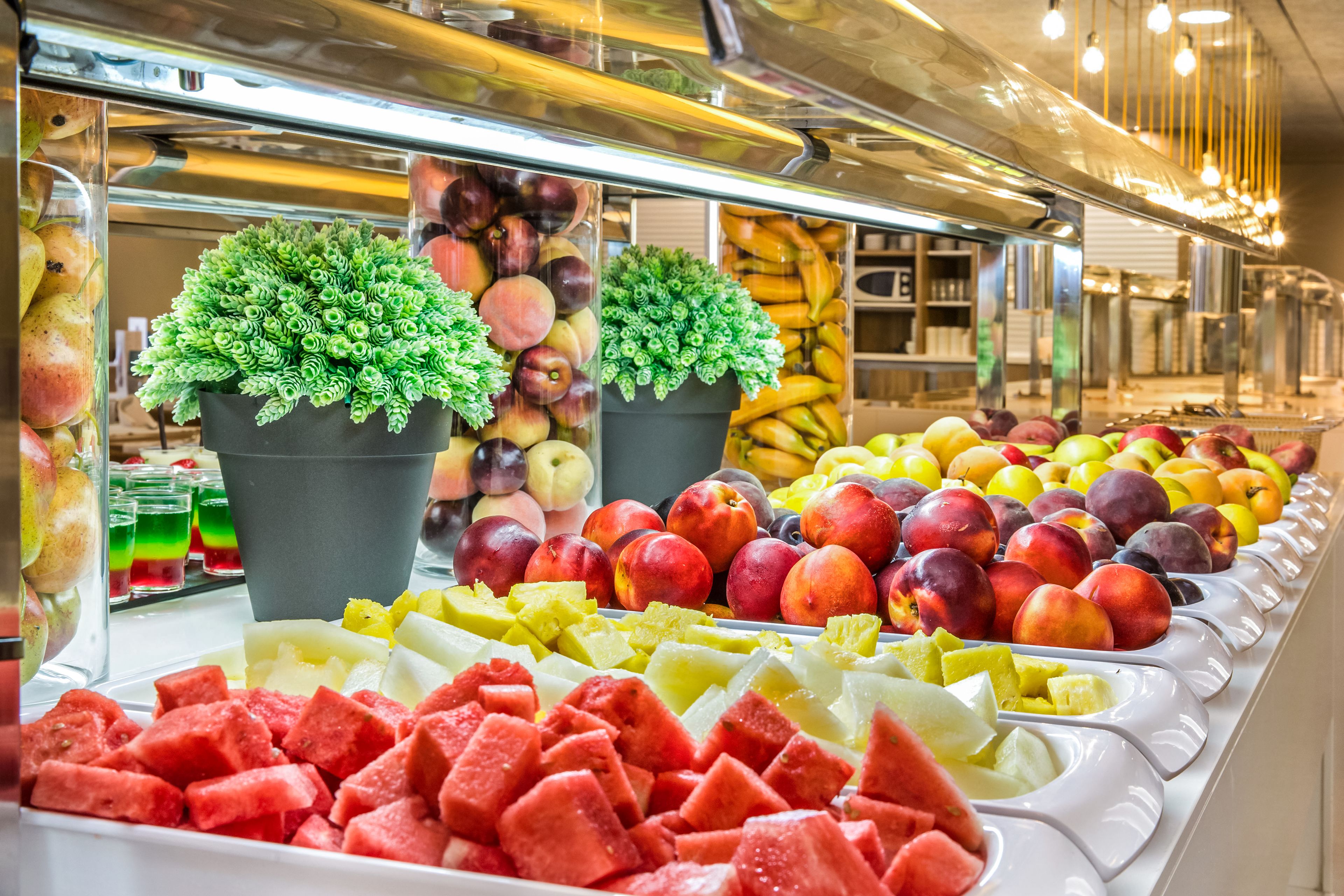 Una exhibición de frutas con diversas frutas y una planta en maceta.