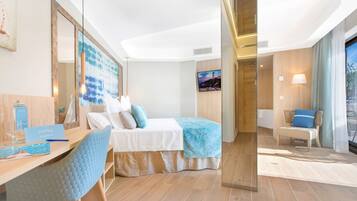 A modern hotel room with a bed, a desk with a chair, a large mirror, a television, and a window with curtains.