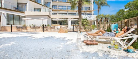 Un resort con mobiliario exterior, palmeras y un edificio con balcones.