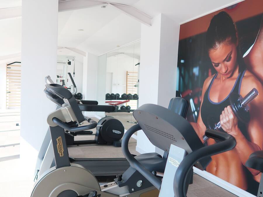 A gym with cardio machines, weightlifting equipment, and a large mirror.