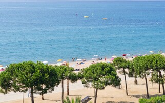 Una playa cerca, arena blanca, sombrillas, toallas de playa
