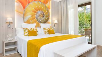 Een hotelkamer met een groot bed, een nachtkastje met een telefoon, en uitzicht op groen door het raam.