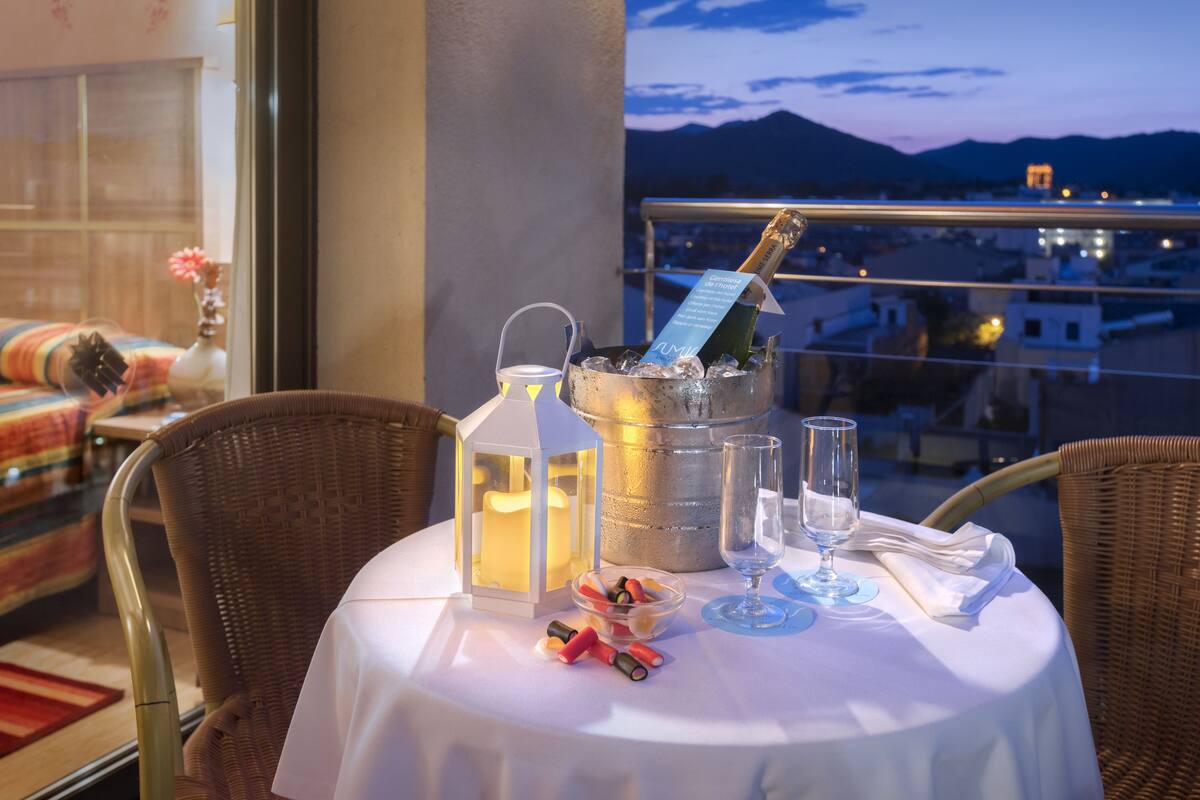 A balcony table with a bottle of champagne, a lantern, and a bowl of snacks.