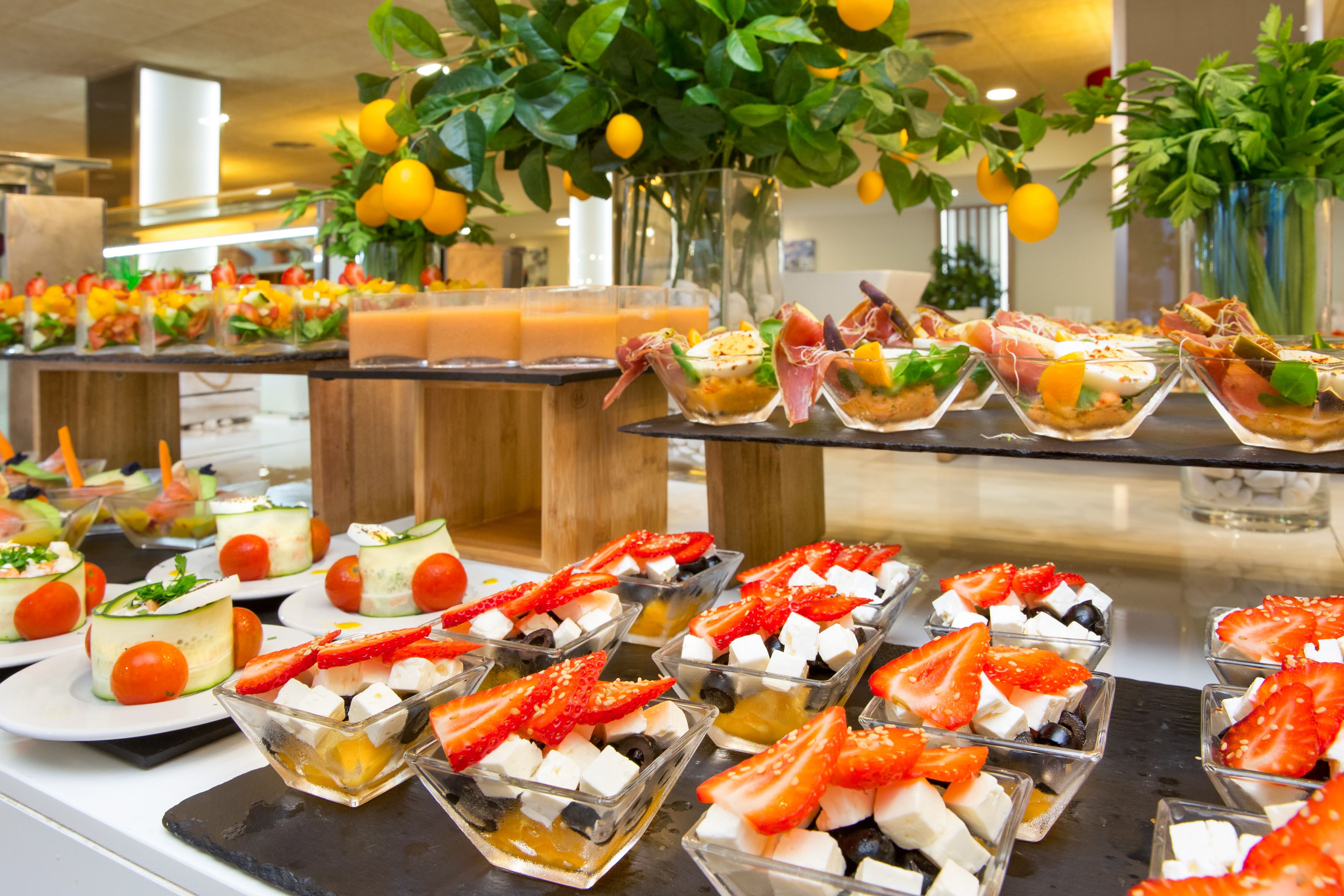 Un bufé con diversas opciones de comida, incluyendo fruta, queso y otros bocadillos.