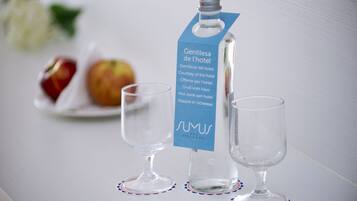 A bottle of water with a label and two empty glasses on a table.