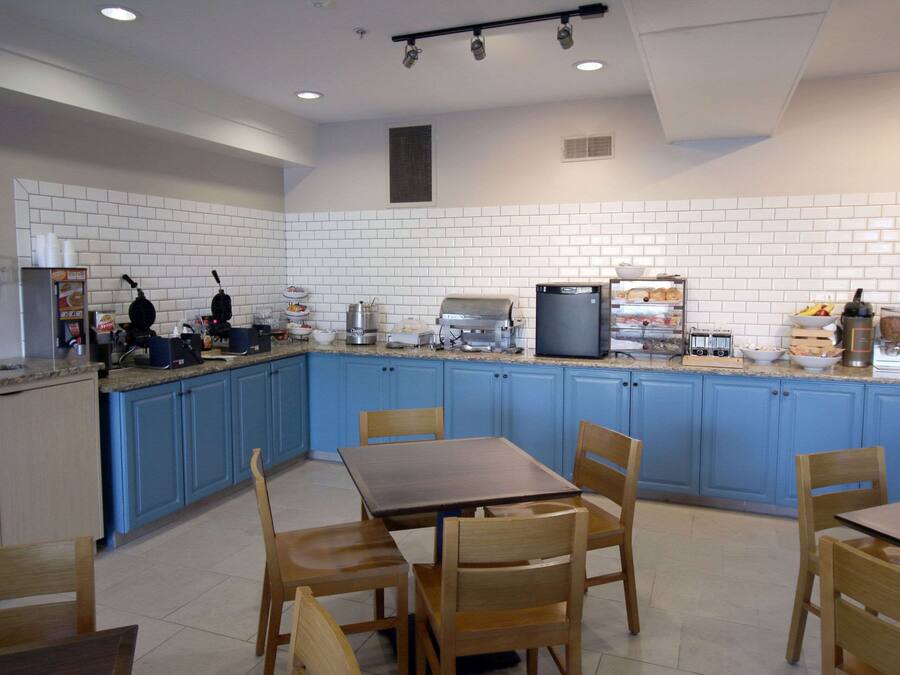 Una cocina moderna con armarios azules, encimera de granito y sillas de madera.