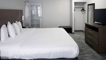 A hotel room with a large bed, a television, a wardrobe, and a door leading to a bathroom.