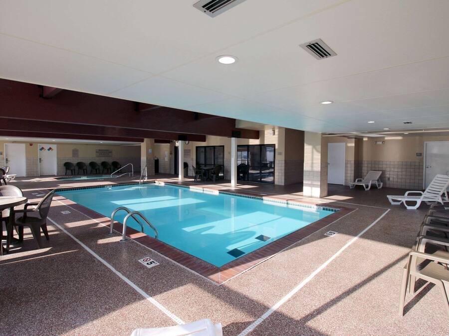 Une piscine intérieure avec des couloirs bien délimités, des chaises longues et un espace détente avec des tables.