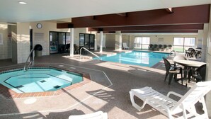 An indoor swimming pool with multiple lanes, lounge chairs, and a seating area with tables. - Country Inn & Suites by Radisson, Council Bluffs, IA (Council Bluffs)