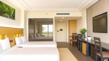 Une chambre d’hôtel avec un grand lit, un bureau avec une chaise, une télévision et une fenêtre donnant sur l’extérieur.