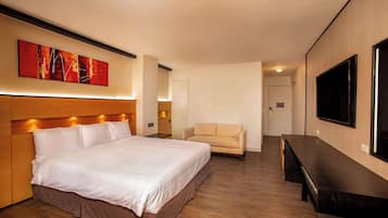 Een hotelkamer met een groot bed, een sofa, een televisie en een houten vloer.