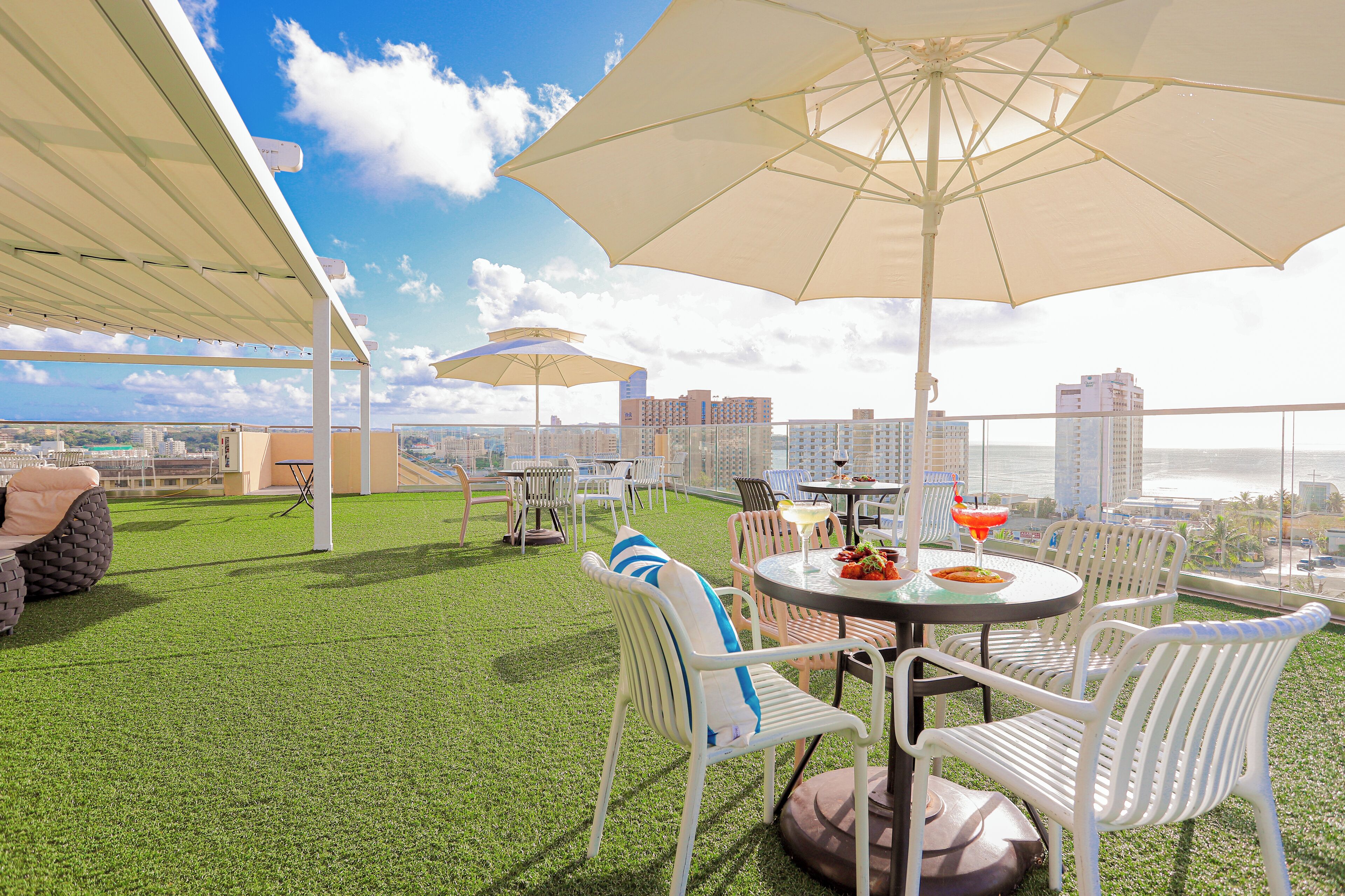 A rooftop terrace with outdoor seating, umbrellas, and a city view.