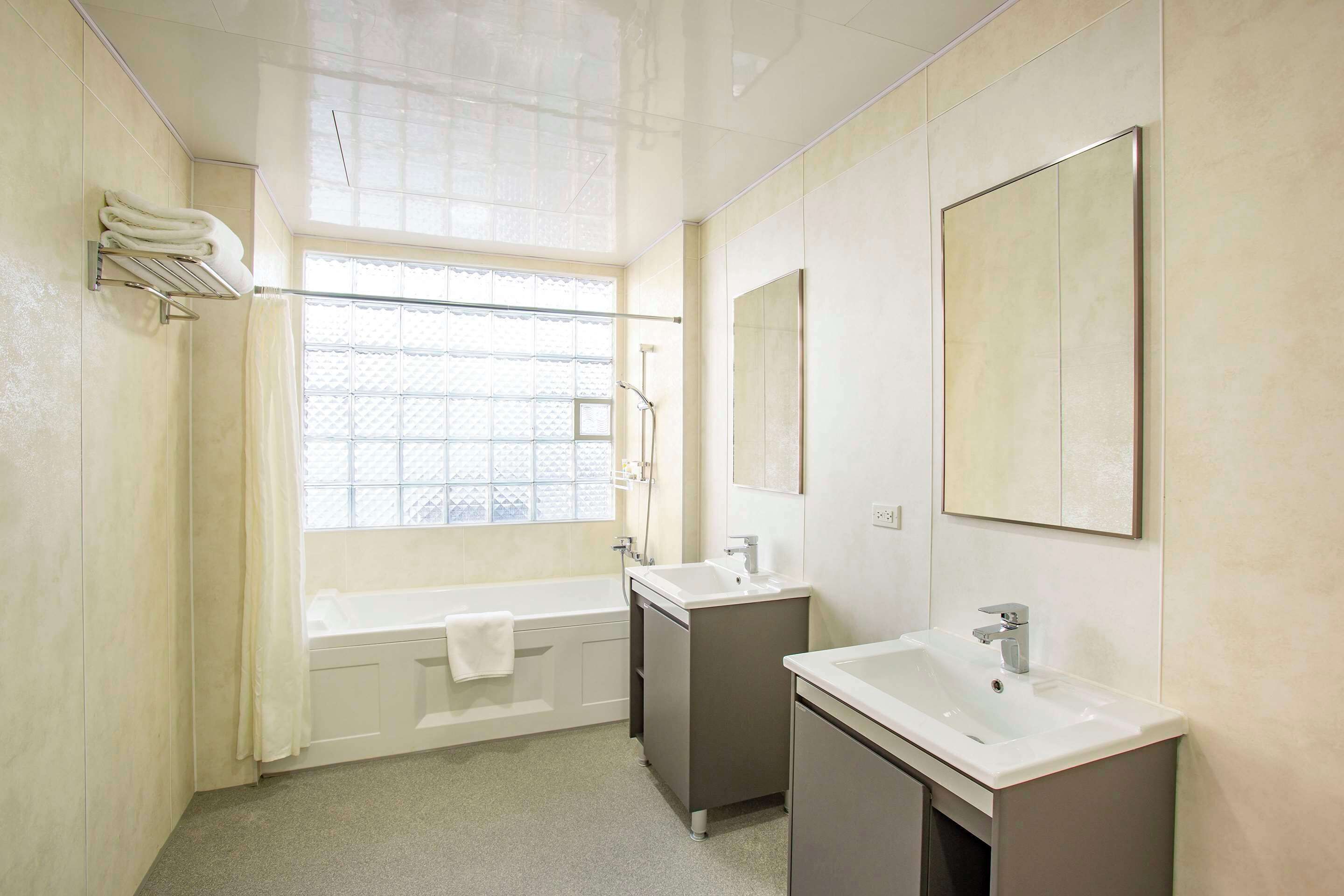 Un baño con bañera, dos lavamanos y un ventanal amplio.
