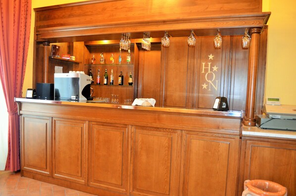 Una zona de bar con un mini refrigerador, utensilios para coctelería y una caja registradora.