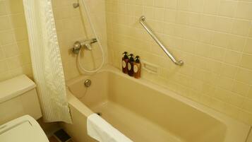 A bathroom with a bathtub, a shower, and a toilet. There are two bottles of soap on the wall.