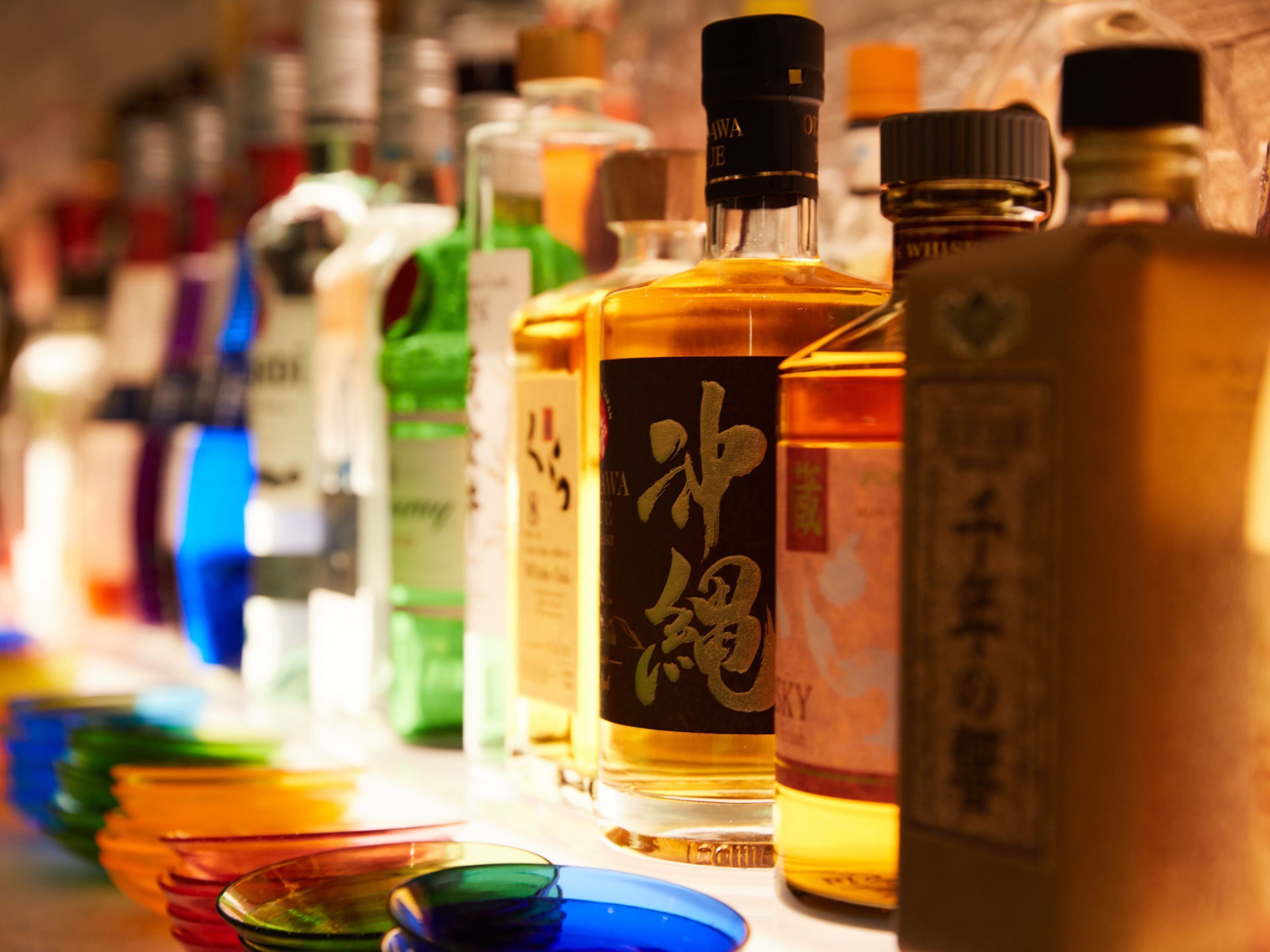A variety of liquor bottles with labels, arranged on a table.