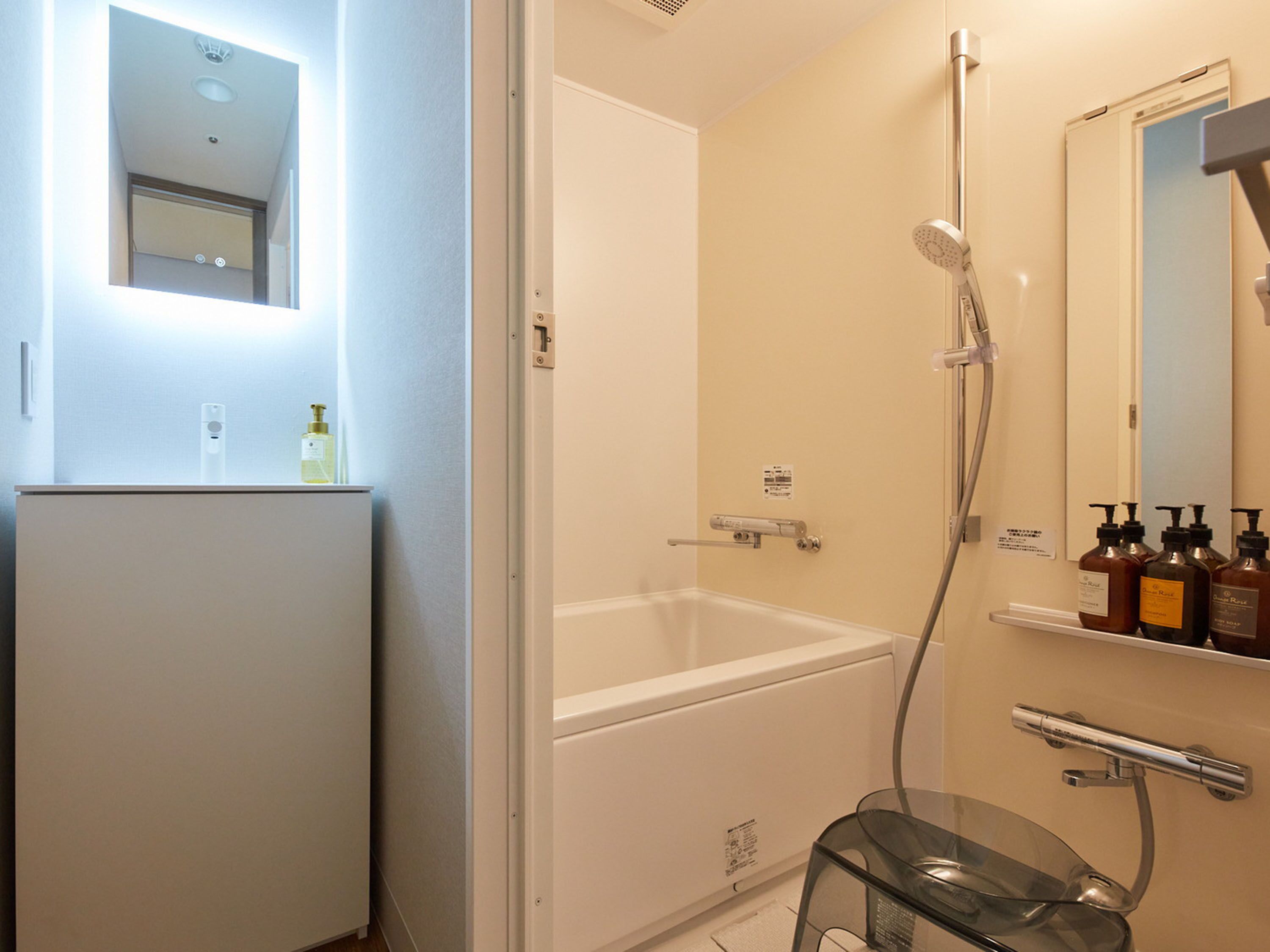 Une salle de bain moderne avec une douche à l’italienne en verre, une baignoire blanche et un miroir au-dessus du lavabo.
