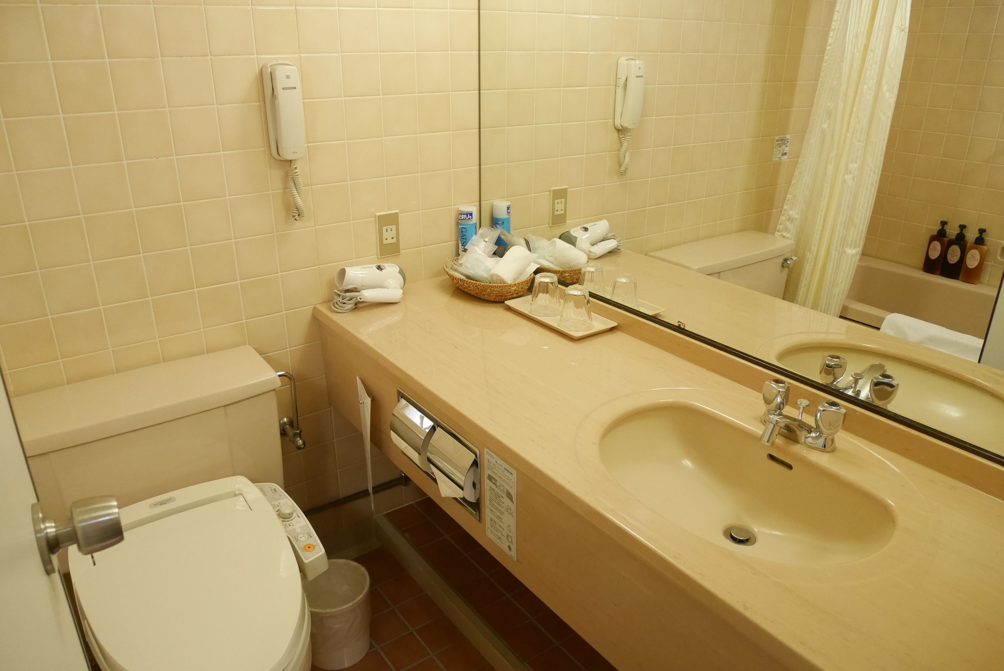 A bathroom with a beige sink, a mirror, a toilet, and a shower curtain.