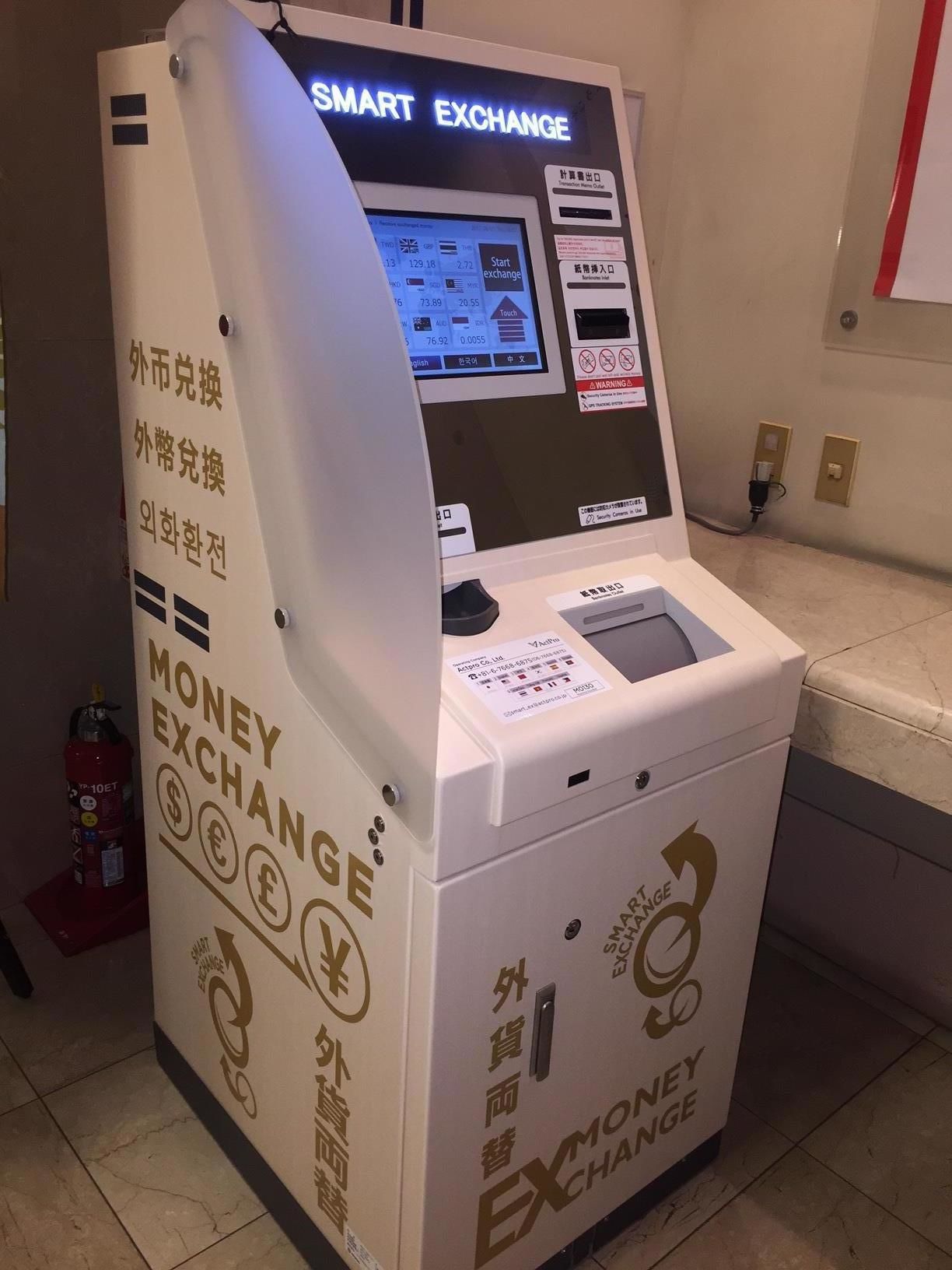 A money exchange machine with a digital display and multiple currency options.