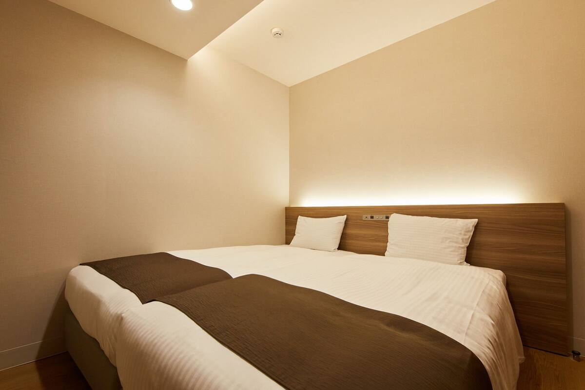 Een hotelkamer met een groot bed, een houten hoofdbord en een plafondlamp.
