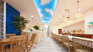 A modern bar area with a high ceiling and a sky-like ceiling design, wooden furniture, and a bar counter with various bottles.