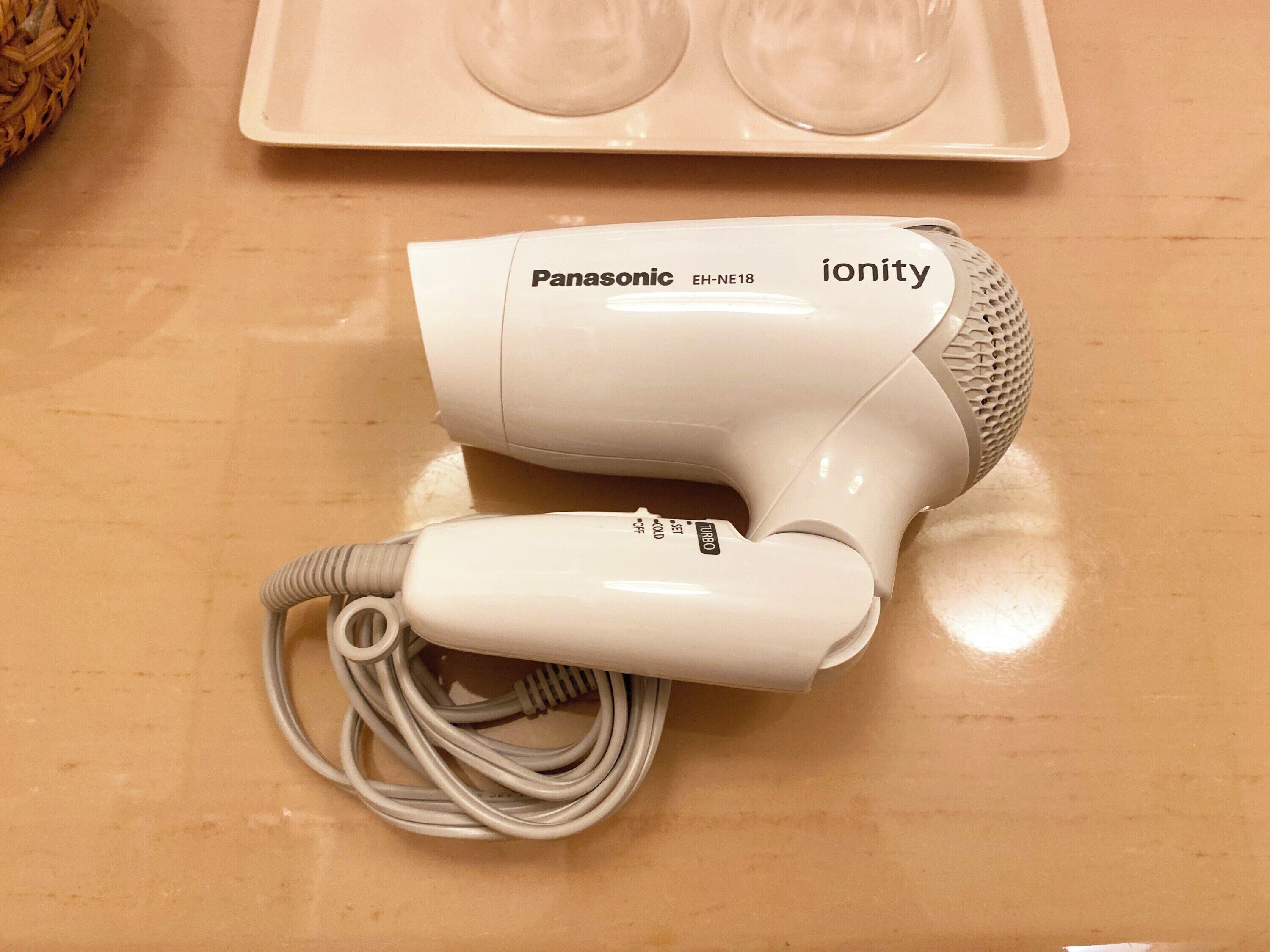 A Panasonic ionity hair dryer with a cord on a wooden surface.