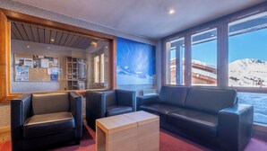 A modern lobby with leather sofas, a wooden coffee table, and a bulletin board with notices.