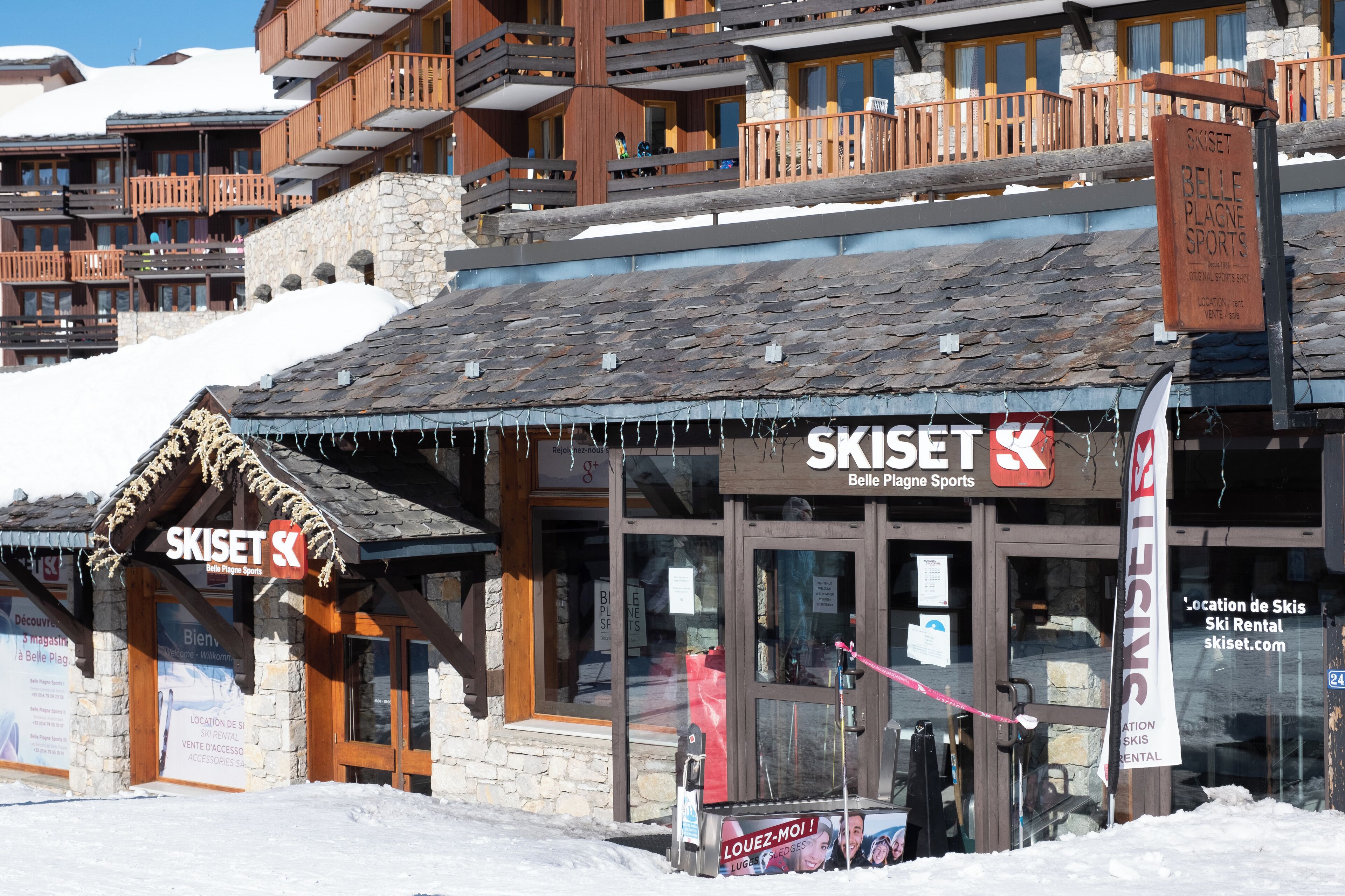 Een winkel voor het huren van ski's, SKISSET geheten, met een gevel van steen en houten balkons.