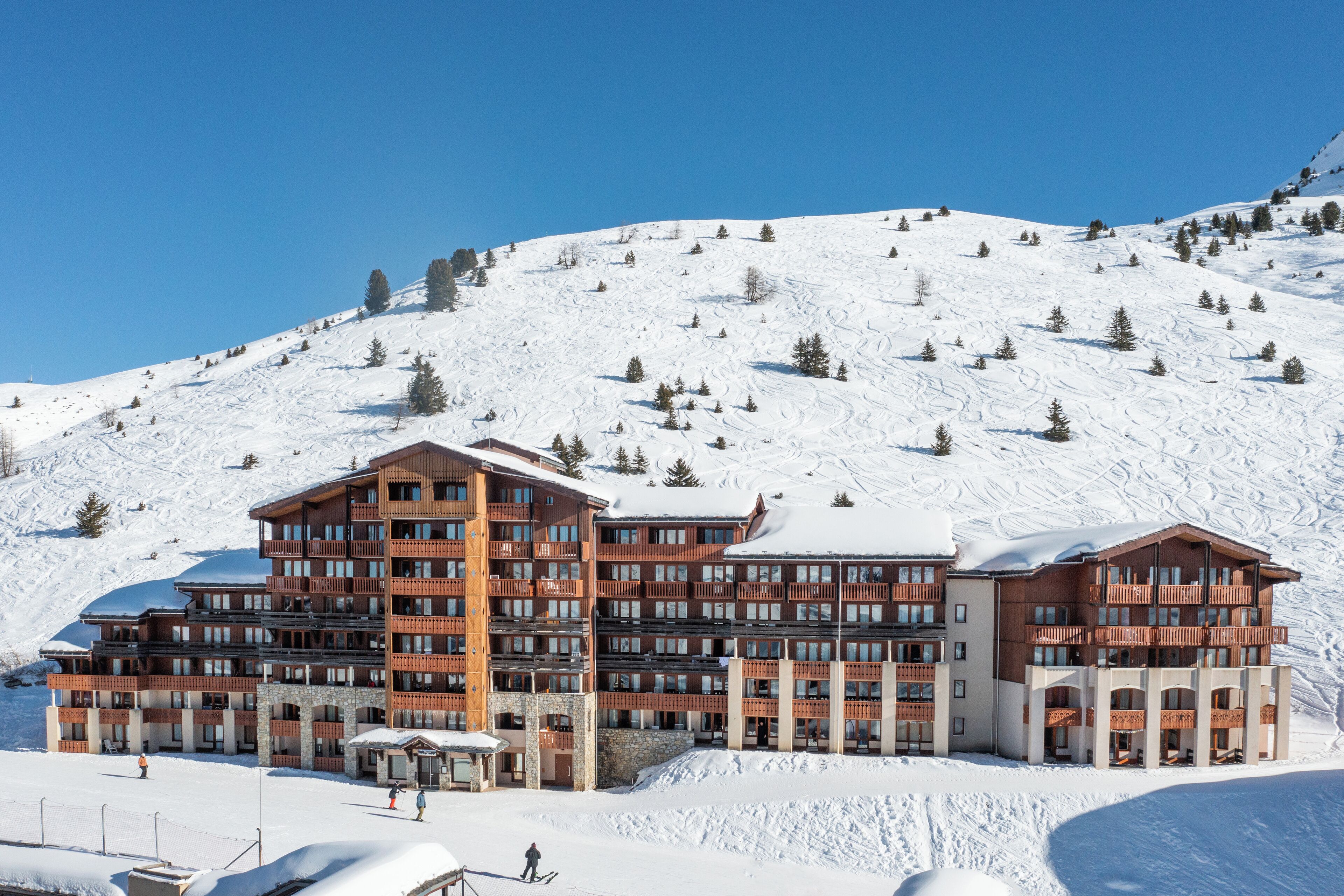 A multi-story hotel with a ski slope in the background.
