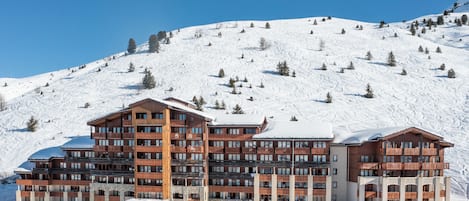 A multi-story hotel with a ski slope in the background.