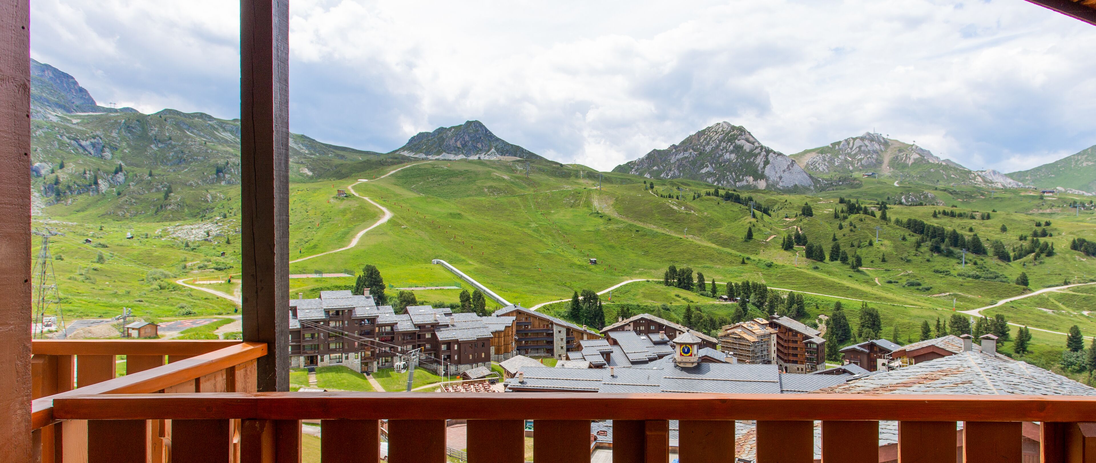 A mountain village with traditional wooden buildings, a winding road, and a view of the surrounding hills.