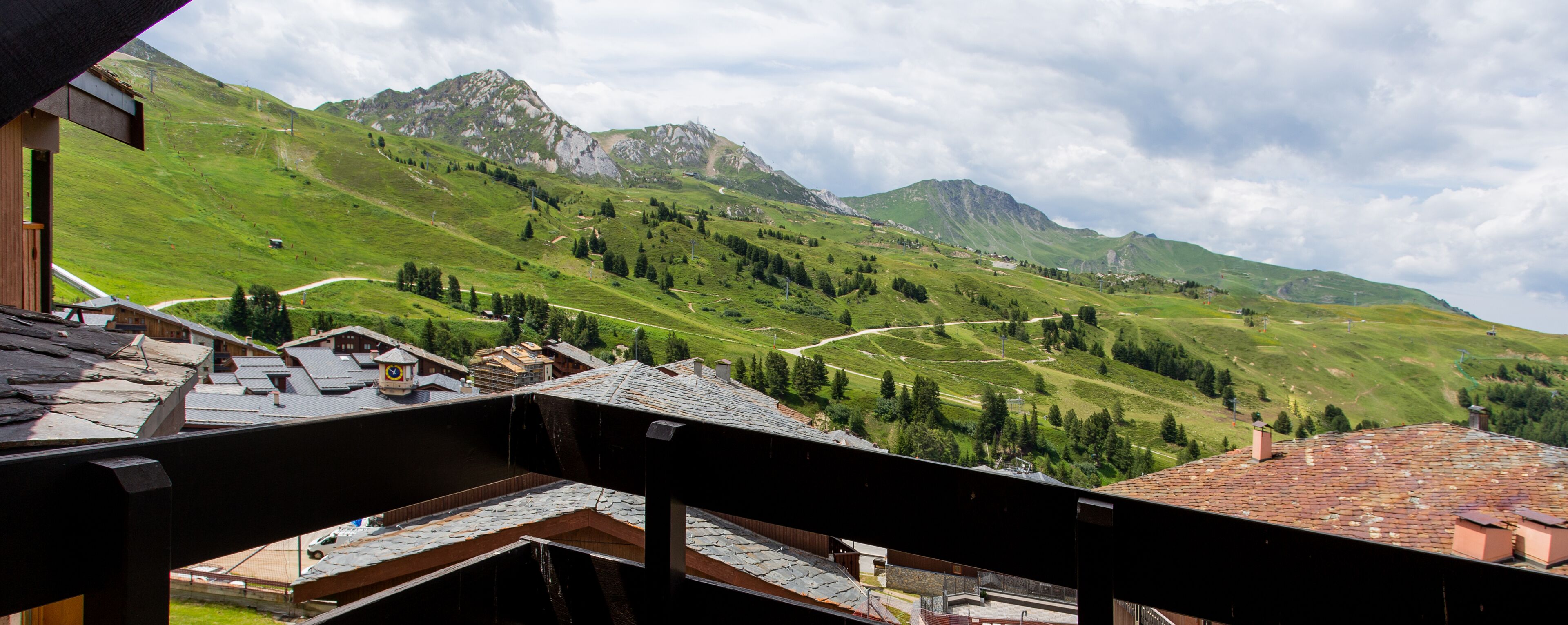 A mountainous landscape with a winding road, a small village, and a prominent mountain peak.