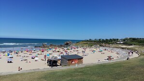 A beach with umbrellas, people, and a small wooden structure. - Résidence Ilbarritz (Bidart)
