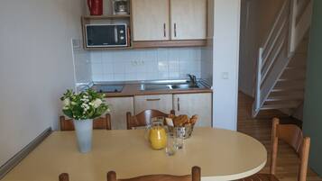 A kitchen with wooden cabinets, a microwave, a coffee maker, and a dining table with chairs.