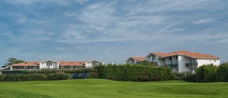 A modern residential complex with multiple houses, a well-maintained lawn, and a clear sky.