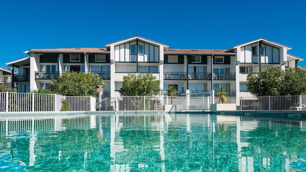 A hotel with a clear swimming pool, multiple balconies, and a well-maintained exterior. - Résidence Ilbarritz (Bidart)